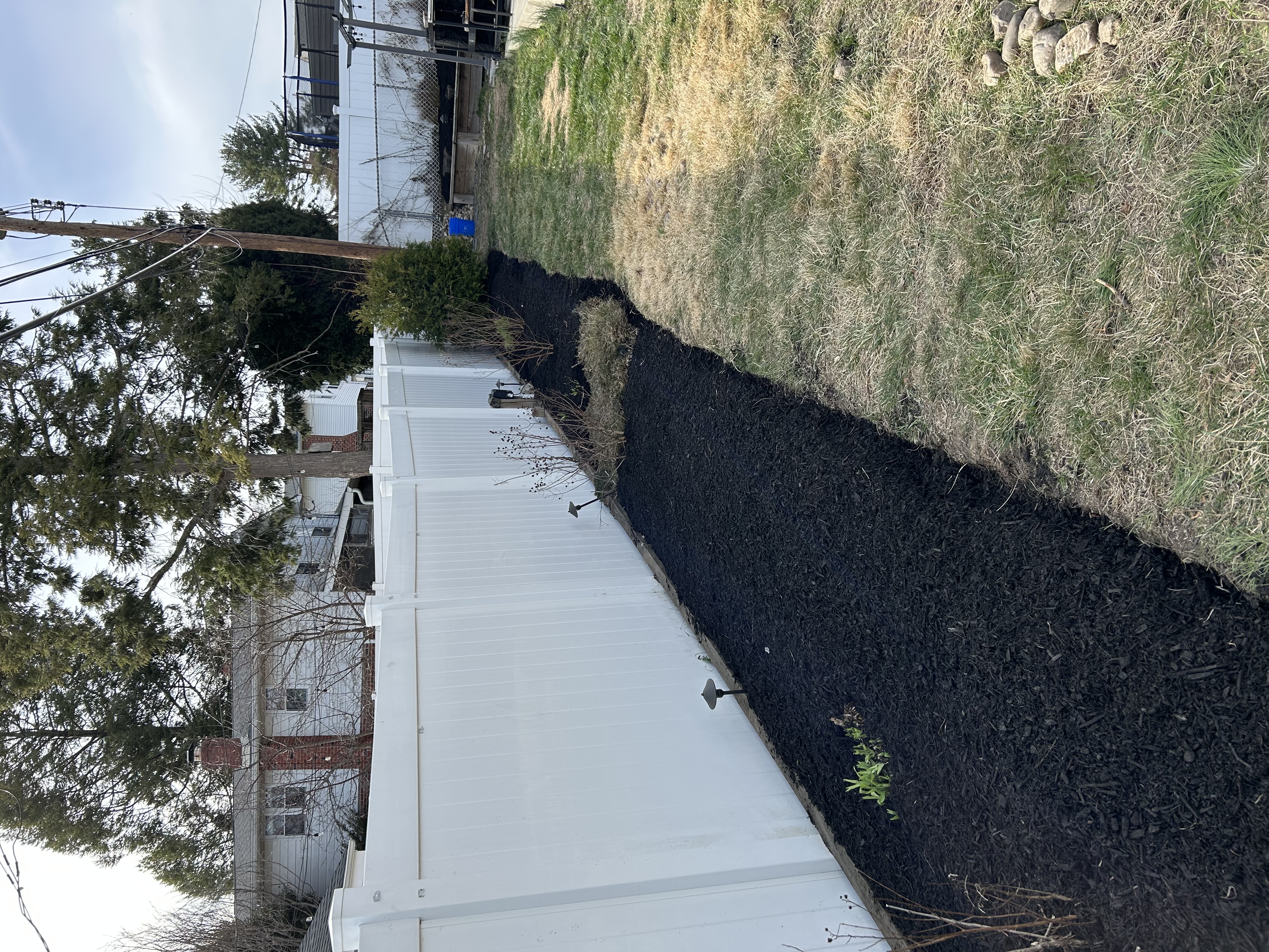 Mulch bed running along white fence