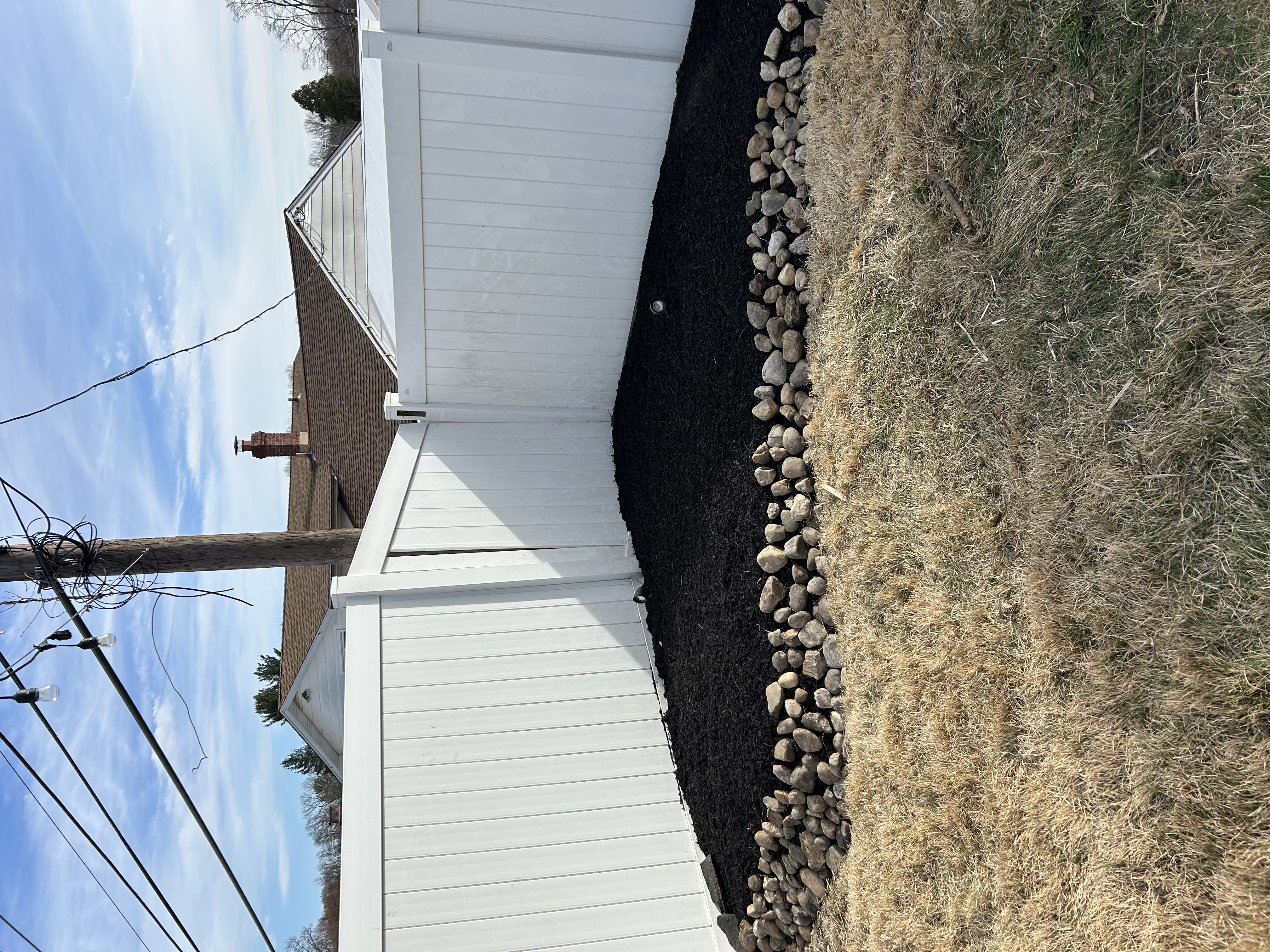 Fence line mulch bed with river rock border