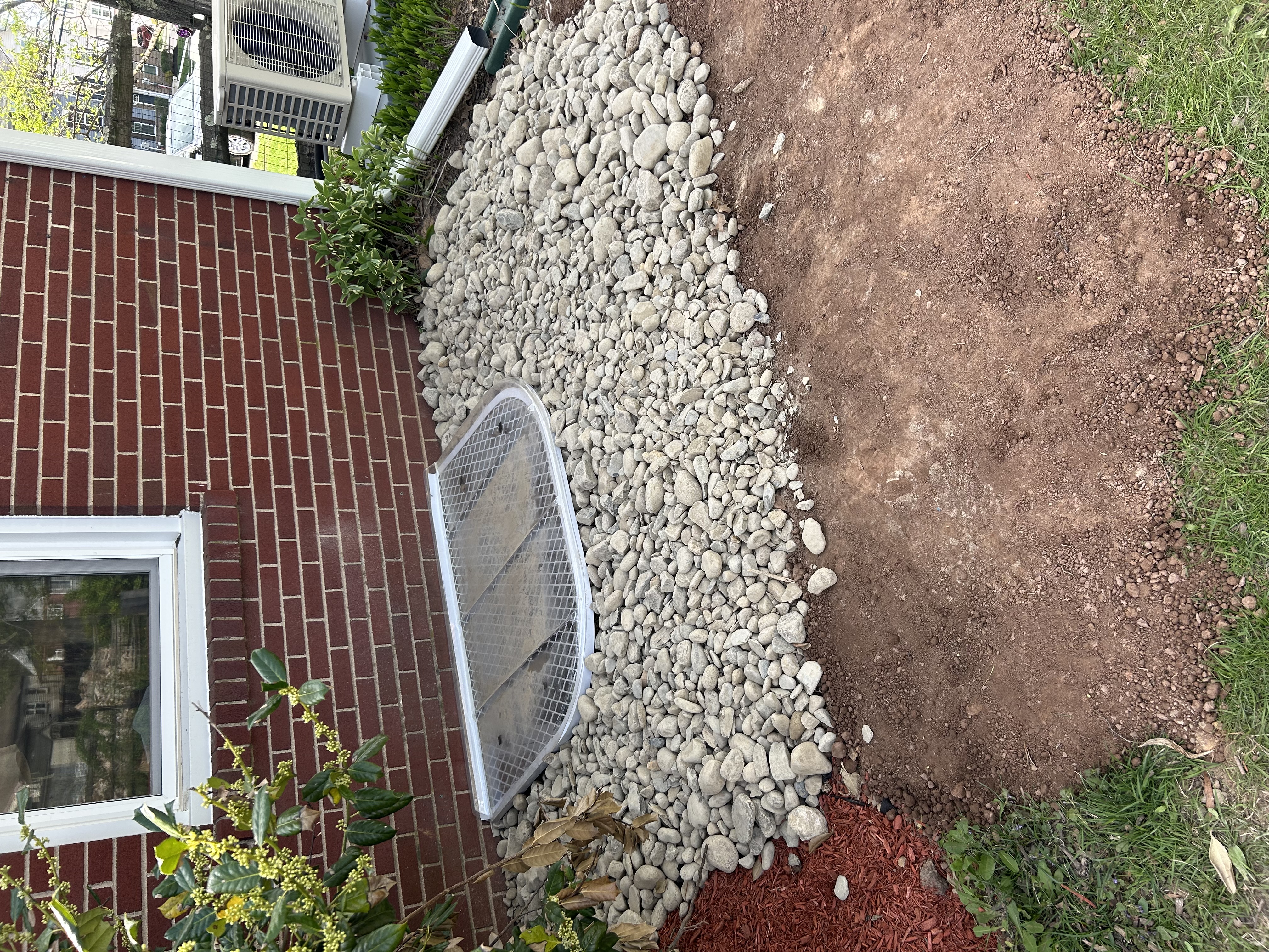 River rock drainage bed along brick foundation